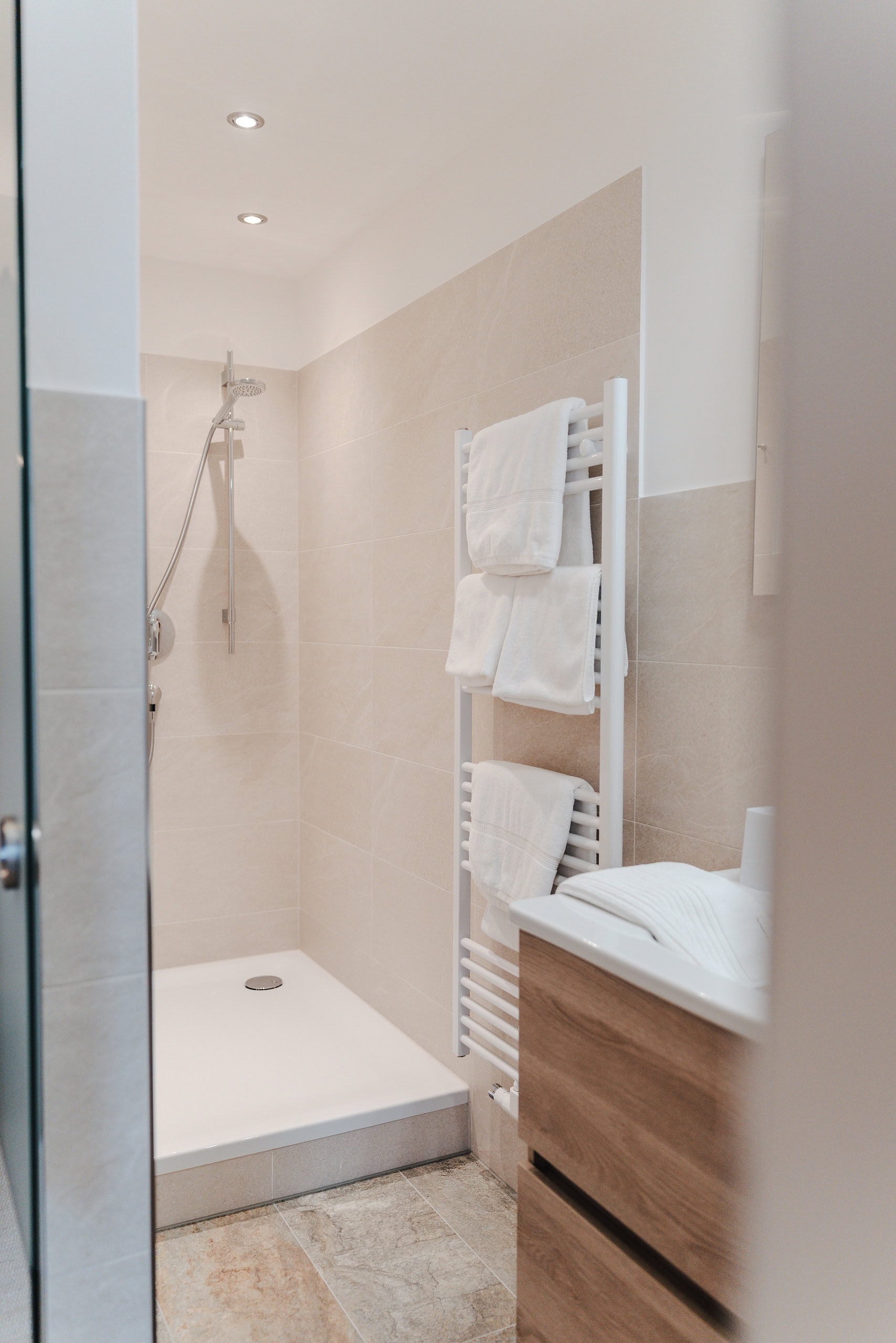 Helles Badezimmer mit Dusche, Handtüchern und moderner Einrichtung im Gästehaus Reit im Winkl.
