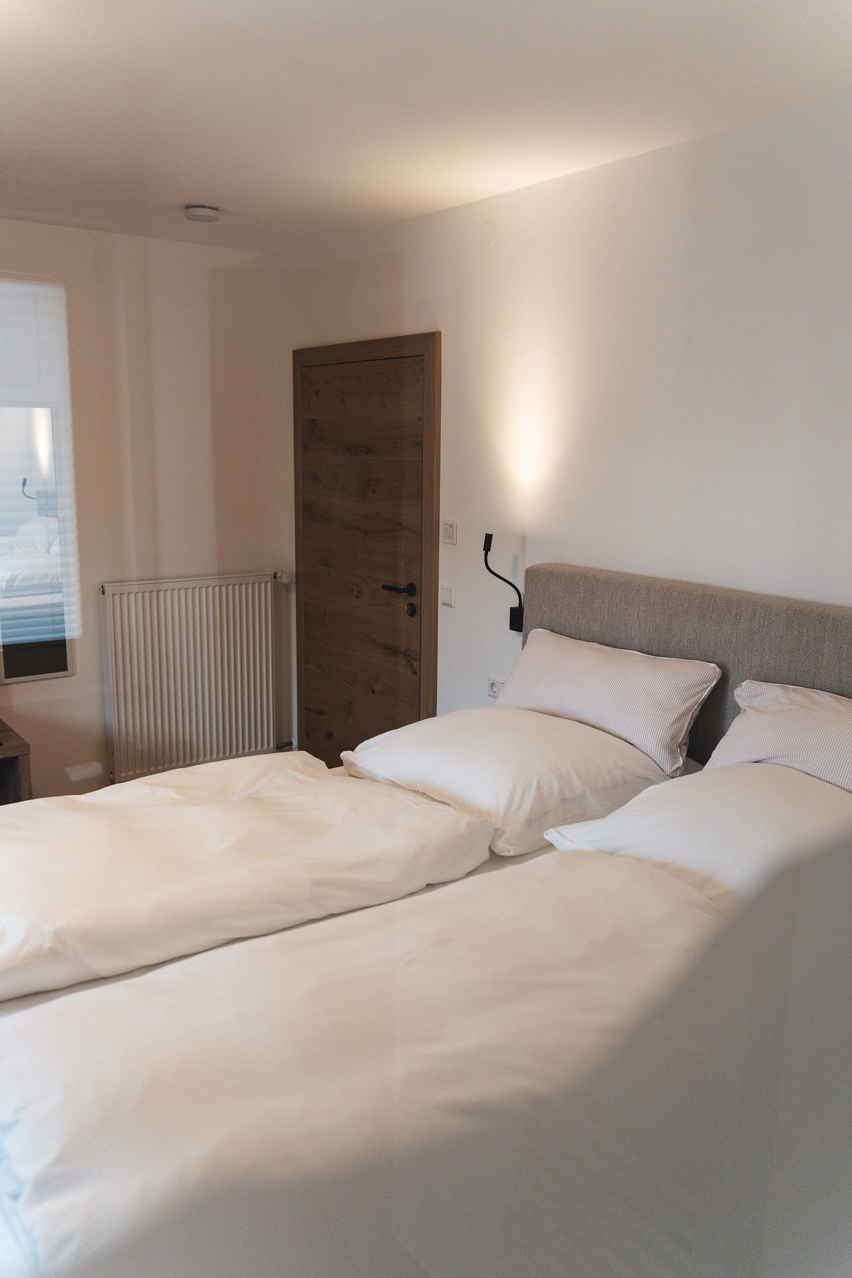 Schlafzimmer mit zwei Betten, moderner Beleuchtung und natürlichem Licht in Reit im Winkl.