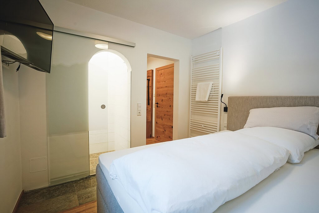 Gem&uuml;tliches Schlafzimmer im G&auml;stehaus mit modernem Komfort und Blick auf den Flur.