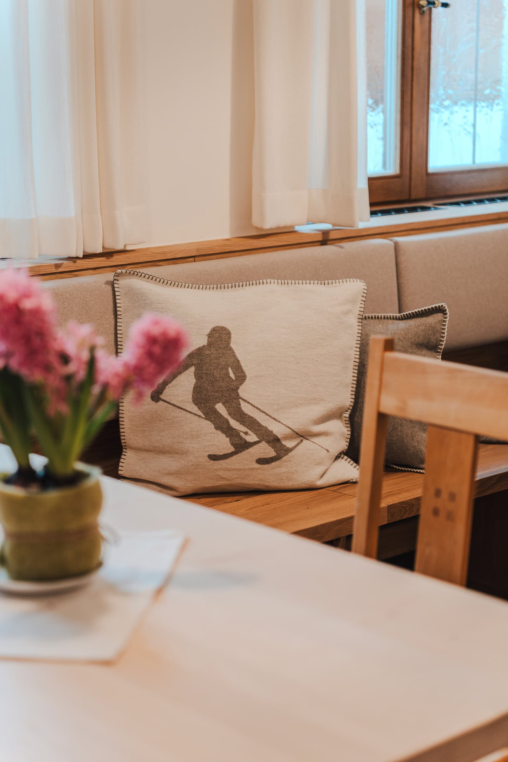 Gemütliche Sitzecke mit Kissen im Gästehaus, Blick auf Fenster und Natur.