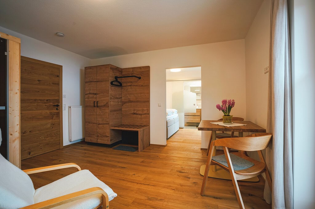 Gem&uuml;tliches Zimmer im G&auml;stehaus am Kurparkweg, mit Holzm&ouml;beln und Blick auf den Innenraum.