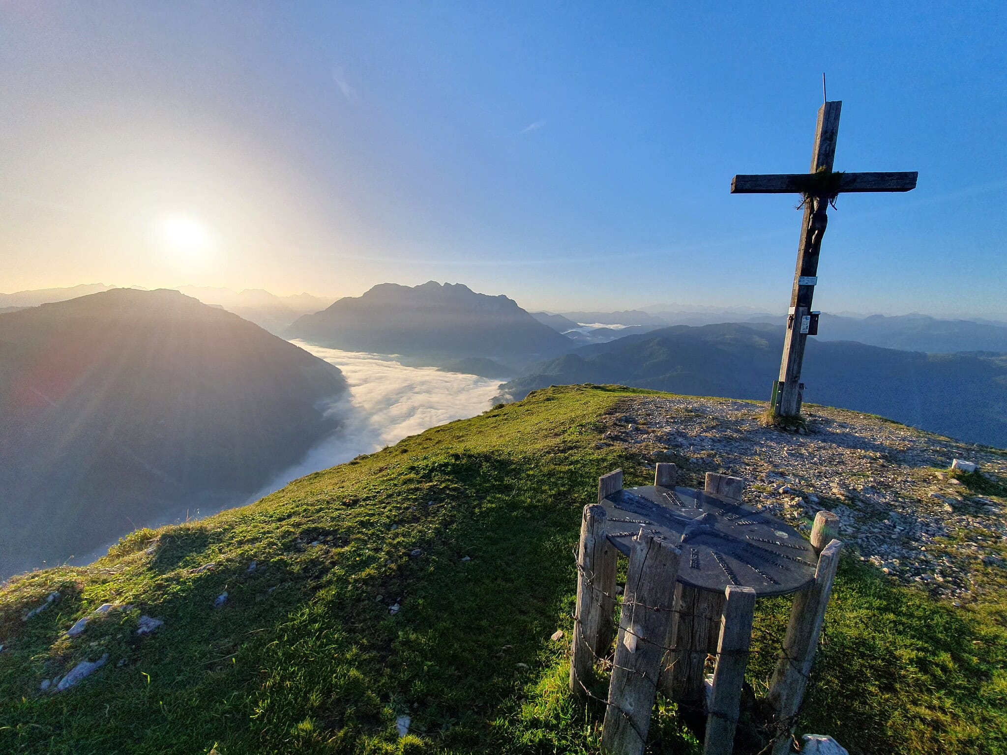Gipfelkreuz auf dem Reit im Winkl Berg mit Blick auf die Berge bei Sonnenaufgang.