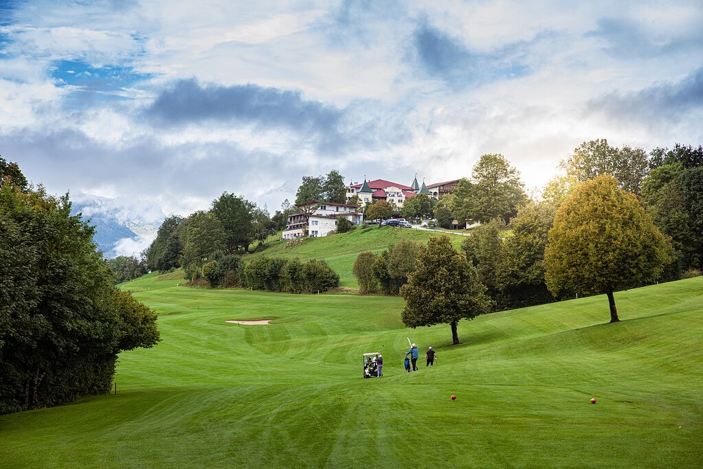 Gästehaus am Kurparkweg in Reit im Winkl, mit Blick auf die grüne Golfanlage und das malerische Berg.