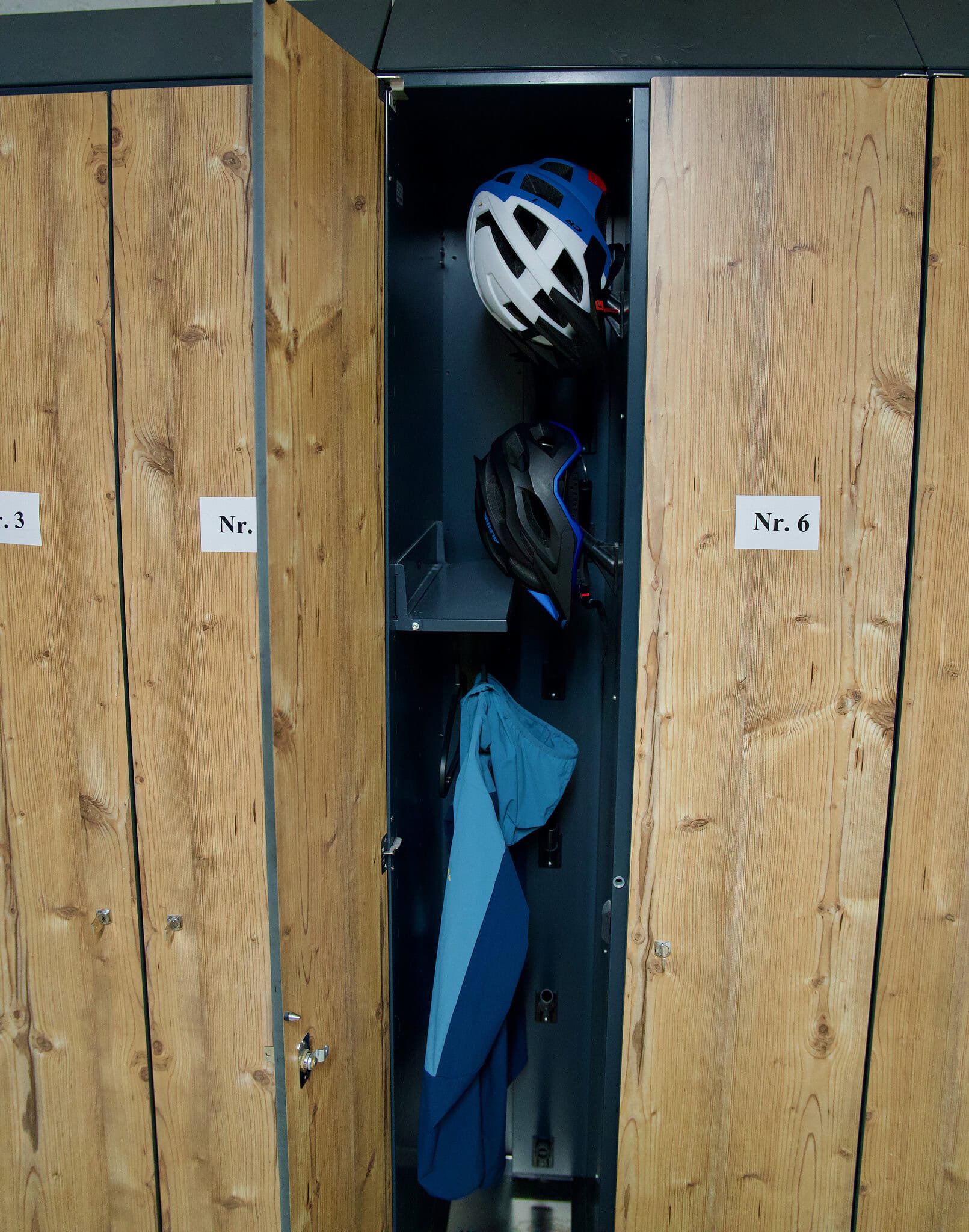 Fahrradhelme und Ausrüstung in einem Holzschließfach am Gästehaus.
