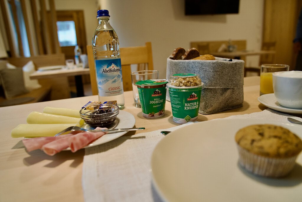 Fr&uuml;hst&uuml;ckstisch mit Kaffee, Wasser, Joghurt und Geb&auml;ck im G&auml;stehaus.