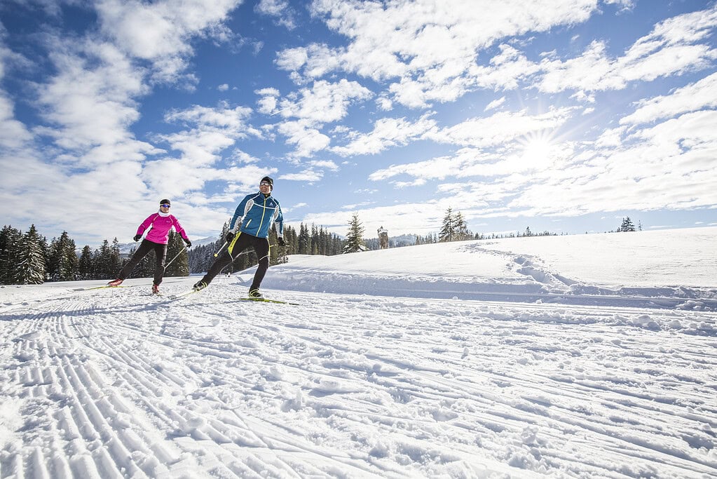 Skifahrer auf verschneitem Pistenabschnitt bei Sonnenschein in Reit im Winkl.